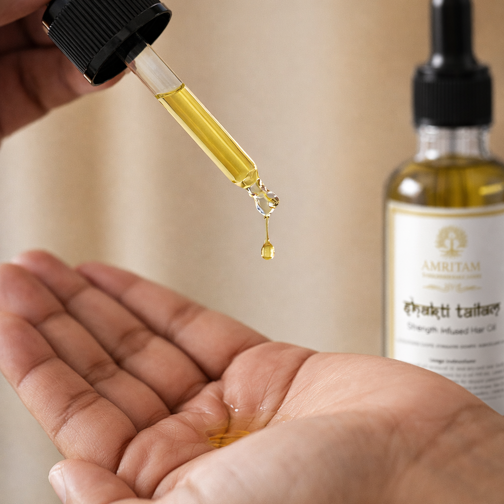 Hand holding a dropper with oil over another hand, with a bottle of oil in the background.